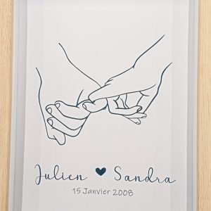 cadre en bois effet 3D avec une image de deux mains homme et femme qui se tiennent par les petits doigts. en dessous sont écrits les prénoms des deux personnes avec un coeur entre les deux et la date de rencontre ou mariage. effet doré